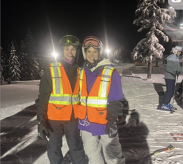 A picture of Nina Steyn (left) and her guide Bella (right) wearing high visibility vests and Bluetooth headphone sets. 