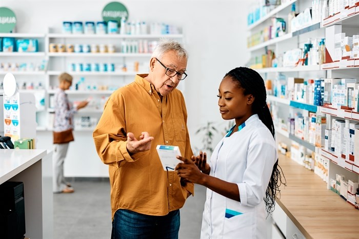 Pharmacist advising senior in pharmacy