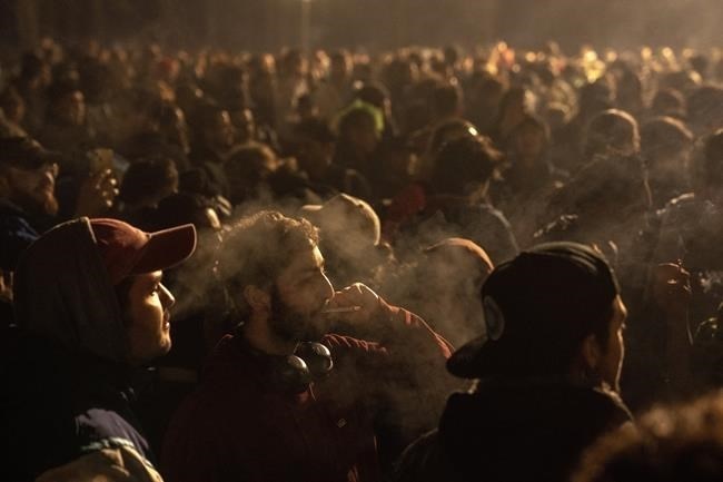People smoke marijuana in front of the Brandenburg Gate during the 'Smoke-In' event in Berlin, Germany, Monday, April 1, 2024. Starting 1 April, Germany has legalized cannabis for personal use. As per the new law, Adults aged 18 and over will be allowed to carry up to 25 grams of cannabis for their own consumption.