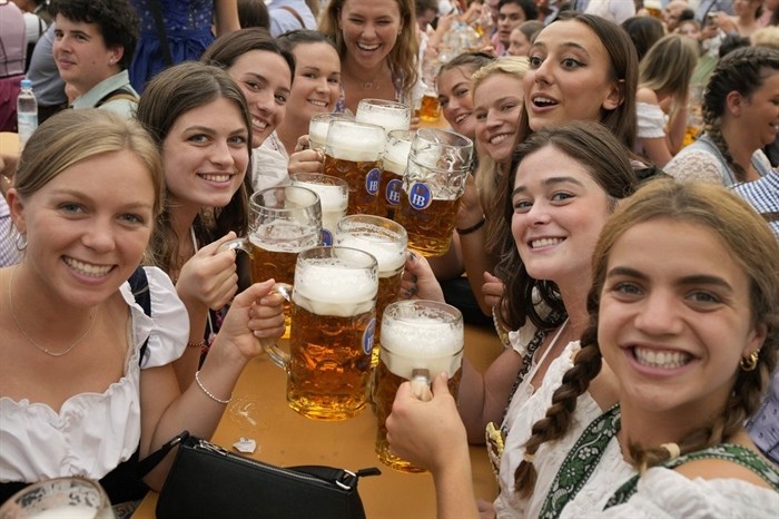 FILE - Women with glasses of beer pose for a photo on day one of the 188th 'Oktoberfest' beer festival in Munich, Germany, Saturday, Sept. 16, 2023. The southern German state of Bavaria will ban the smoking of cannabis at public festivals, inside beer gardens, and even at the world’s most popular beer festival, the Oktoberfest. 