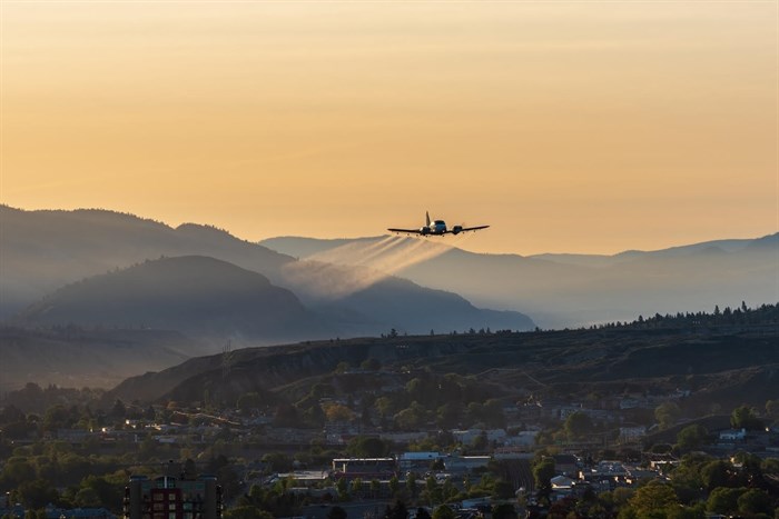 The sun is beginning to brighten the morning sky in Kamloops as a plane drops insecticide. 