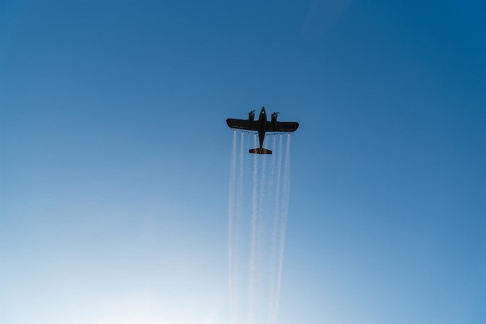 A plane spraying insecticide is shown against a bright blue sky in Kamloops. 