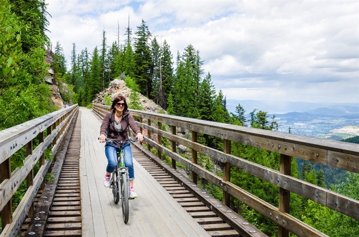 Woman riding a bicycle across Kettle Valley Rail Trail