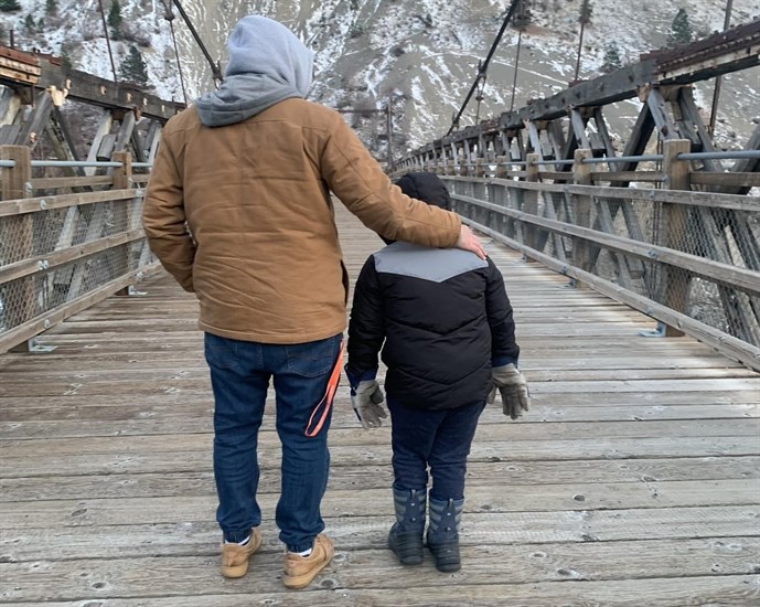 Lillooet resident Rocker Brady stands on a bridge in Lillooet with his young son in December, 2022.