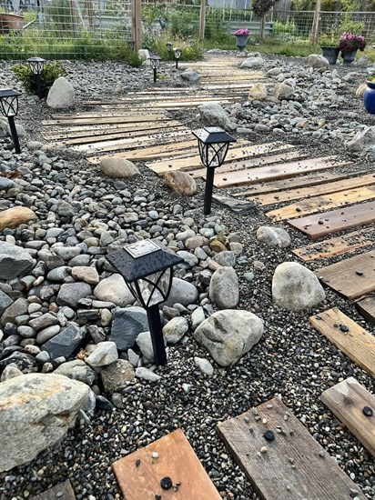 Solar lawn lights line a wooden pathway in Heffley Creek. 