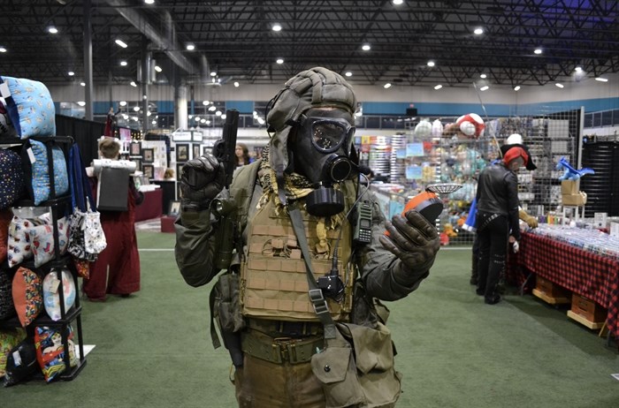 Cosplayer decked out in a gas mask with replica props. 