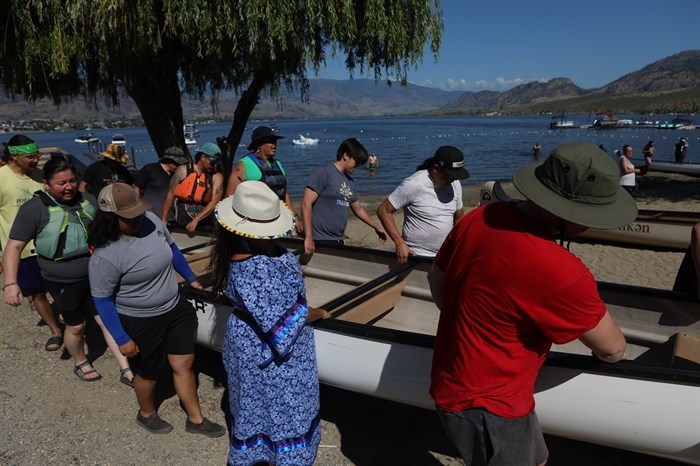 Community members carry a canoe to nk’mip (Osoyoos Lake) in sw?iw?s (Osoyoos) prior to the launch of the 2024 Suk?naqin canoe journey. 