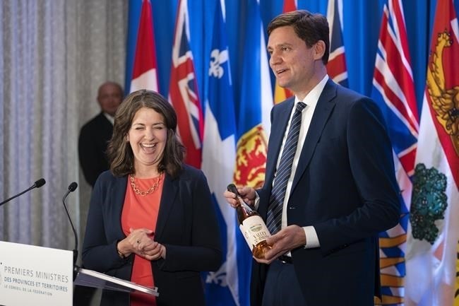 British Columbia Premier David Eby, right, gifts a bottle of B.C. wine to Alberta Premier Danielle Smith while speaking to reporters at the Council of the Federation meetings in Halifax on Tuesday, July 16, 2024.