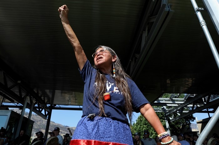 suiki?st Pauline Terbasket, the executive director of the Okanagan Nation Alliance, raises her fist in the air as horseback riders cross into the U.S. from Canada at the Osoyoos-Oroville border in syilx Okanagan homelands on July 20, 2024.