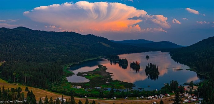 A panoramic view taken from Knouff Lake shows an orange sun behind an interesting cloud formation.