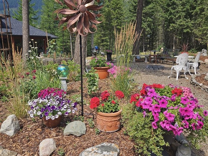 A back yard space in Lumby has lots of natural elements and pots full of blooming flowers. 