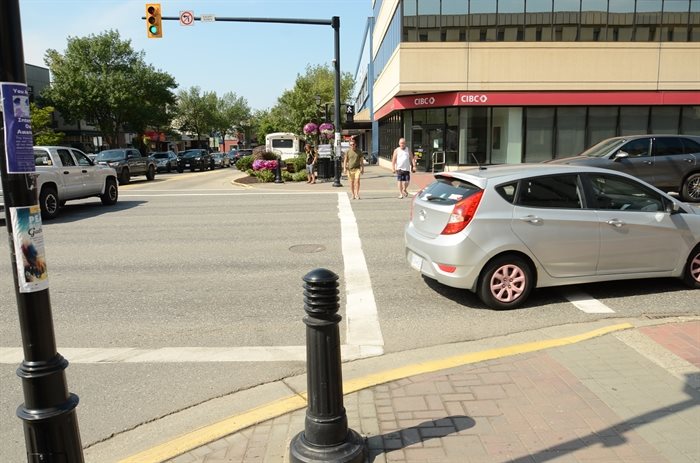 A vehicle takes a right turn as pedestrians cross