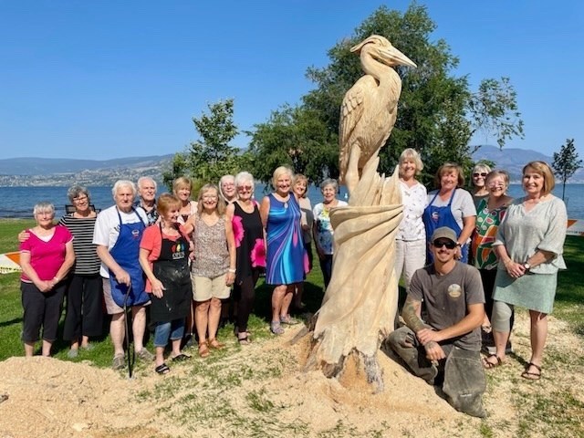 Members of the Sarsons Activity Centre pose in front of a carving by Armstrong's Kamron Garbe at Sarons Beach Park in Kelowna, Aug. 15.