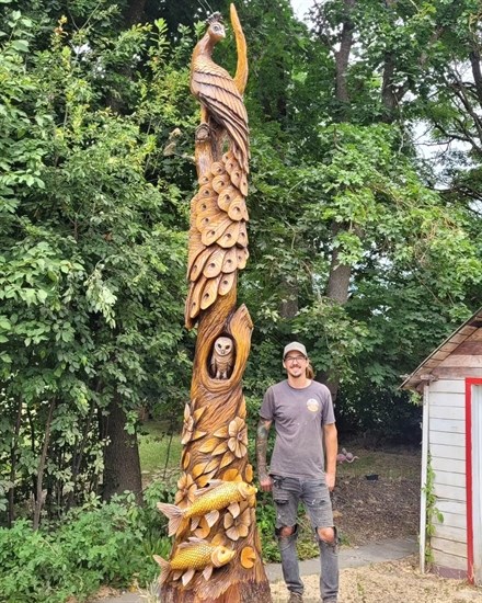 Armstrong woodcarver Kamron Garbe stands beside one of his sculptures in Grinrod. 