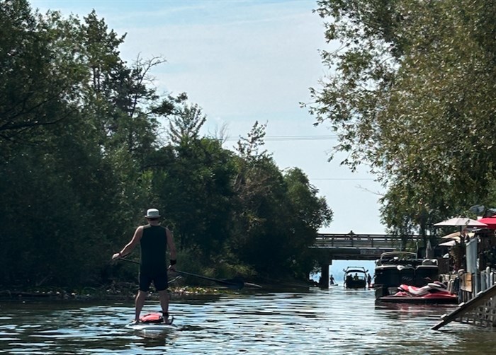 Paddle boarding down the canal while a group of people try to get a boat unstuck in the background.  