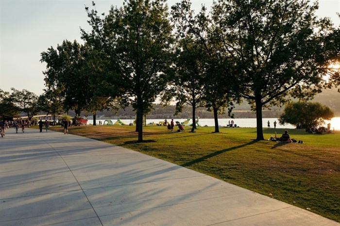 People can be seen enjoying Kelowna City Park as the sun sets in late summer. 