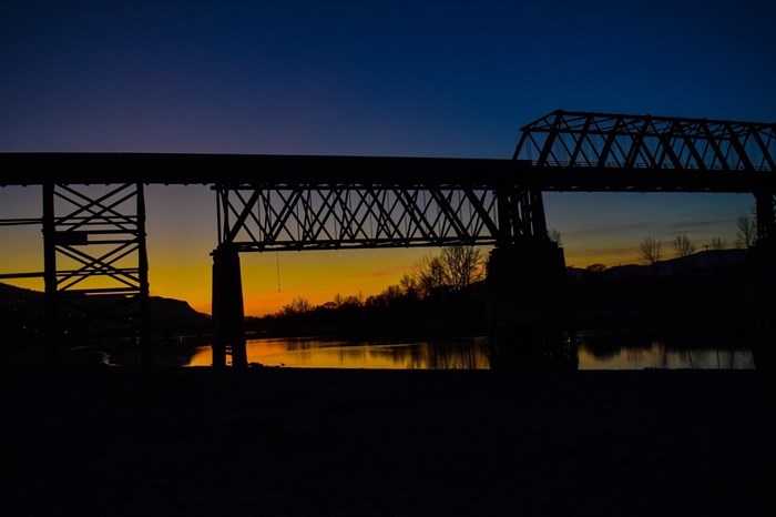 A sunset glows behind the Red Bridge in Kamloops in 2020.
