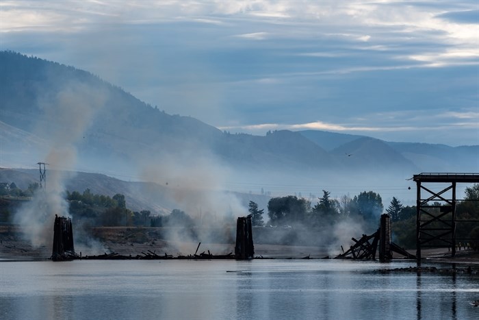 The Red Bridge in Kamloops is seen smoking after burning down on Sept. 19.