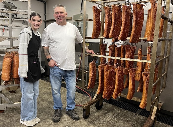 Owner of Gary's European Sausage and Deli in Kamloops, Jurgen Gemsa (right) stands beside employee Haille Baird next to a rack of smoked bacon. 