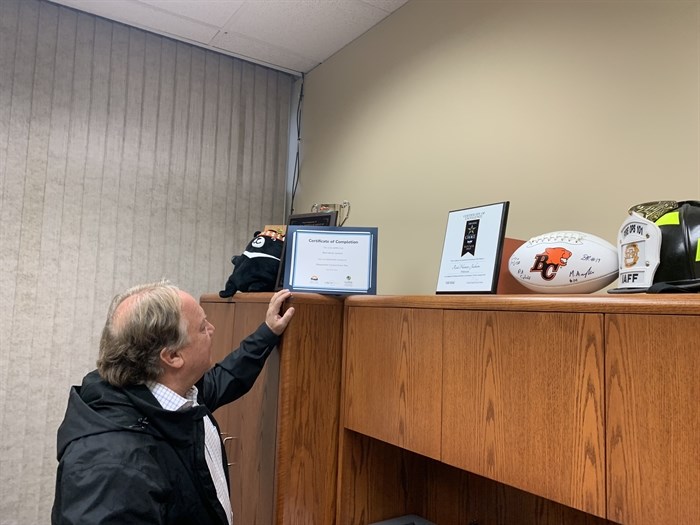 Hamer-Jackson points to a plaque displaying his completion of a workplace conduct course.