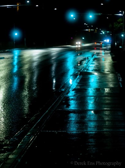 The glow of traffic lights in downtown Kamloops streaks across wet pavement. 