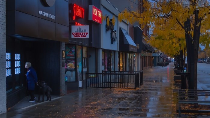 A lady and her dog can be seen in the early morning rain in downtown Kelowna. 