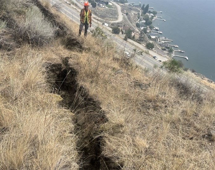 A worker looking at the tension crack in the mountain next to Highway 97.