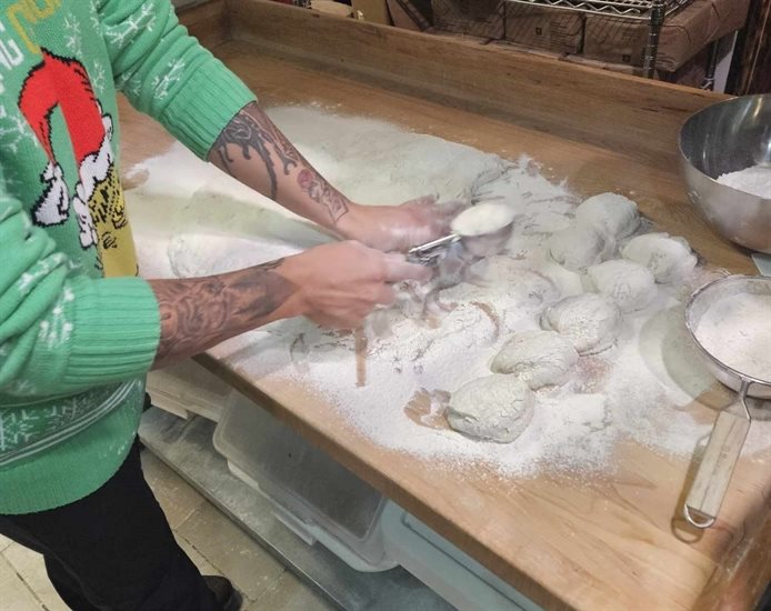 Owner at Kekuli Cafe in Kamloops, Elijah Mack-Stirling portions out dough with an ice cream scoop. 