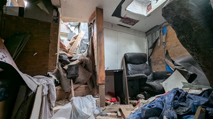 The inside of what was a bedroom with a chair in the corner and skylight above. To the left and out of frame is a raised bed.