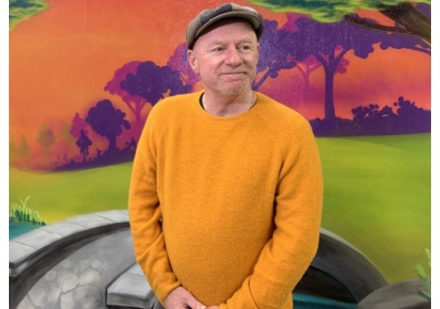 Ask Wellness CEO Bob Hughes stands in front of a mural in the repurposed RV repair shop on Jan. 24, 2025, days before it welcomes shelter residents for the first time.