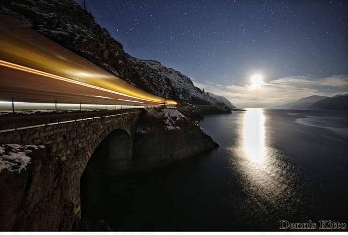 A old train bridge along Kamloops Lake is photographed with a train coming by.