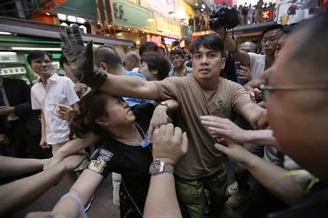 A woman is protected from the crowd by pro-democracy student protesters after a scuffle with local residents in Mong Kok, Hong Kong, Saturday, Oct. 4, 2014. Friction between pro-democracy protesters and opponents of their weeklong occupation of major Hong Kong streets persisted Saturday as police denied they had any connection to criminal gangs suspected of inciting attacks on largely peaceful demonstrators.