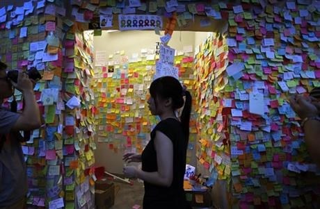 A pro-democracy supporter walks past a wall covered with messages of support, Saturday, Oct. 4, 2014 in Hong Kong.
