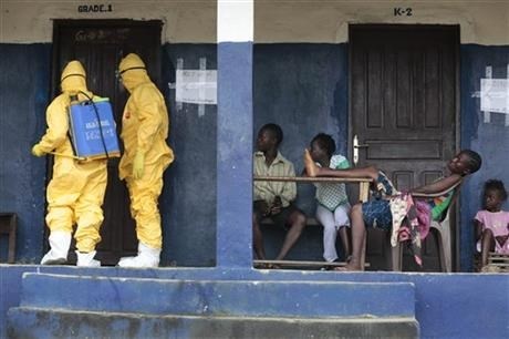 Residents watch members of the ambulance service disinfect a room as they pick up six suspected Ebola sufferers.