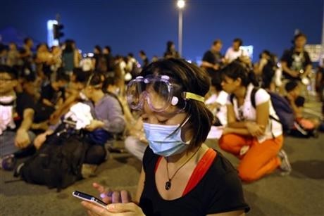 A student pro-democracy protester monitors the news on her smartphone as she and others sit outside Hong Kong's Chief Executive Leung Chun-ying's office, Sunday, Oct. 5, 2014 in Hong Kong.