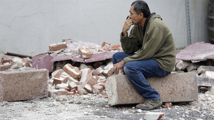 Ron Peralez, of Vacaville, Calif., sits on rubble and looks at earthquake-damaged buildings, in Napa, Calif., Monday, Aug. 25, 2014.