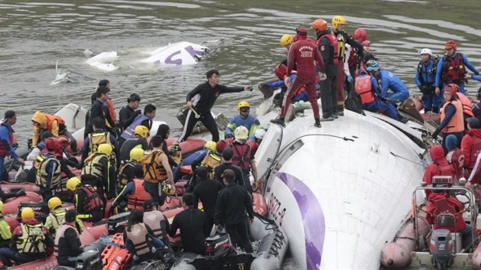 Emergency personnel try to extract passengers from a commercial plane after it crashed in Taipei, Taiwan Wednesday, Feb. 4, 2015. The Taiwanese commercial flight with 58 people aboard clipped a bridge shortly after takeoff and crashed into a river in the island's capital on Wednesday morning.