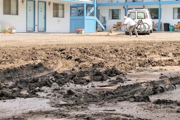 A motel worker shovels the mud from the property's parking lot.