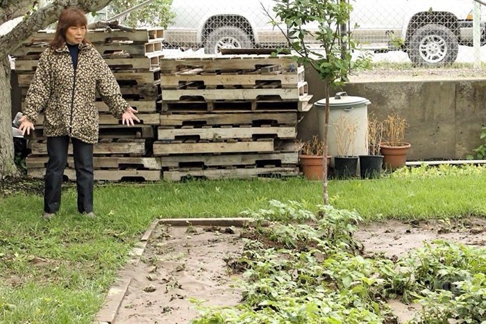 Linkwai Leung stands next to her garden covered in mud.