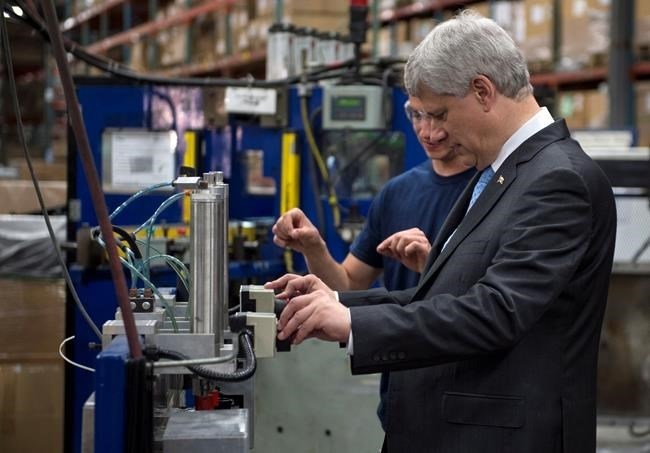 Conservative Leader Stephen Harper gets instructions on how to operate a machine that puts the finishing touch to a radiator while touring a industrial parts manufacture Monday, August 3, 2015 in Laval, Que. 
