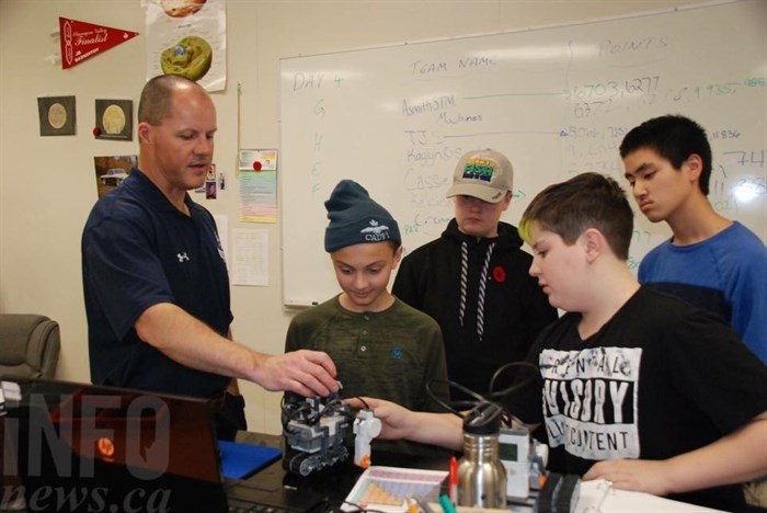Teacher David Coleman helps students program their machines in lego robotics class.