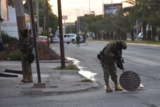 A Mexican navy marine inspects an open manhole after the recapture of Mexico's most wanted drug lord, Joaquin 
