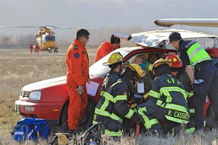A supervisor from RCAF's 442 Squadron watches on as local emergency crews work to help a Rocky Mountain Ranger with a fake neck injury. Crews pretended the car was the cockpit of an airplane involved in a airstrip collision. 