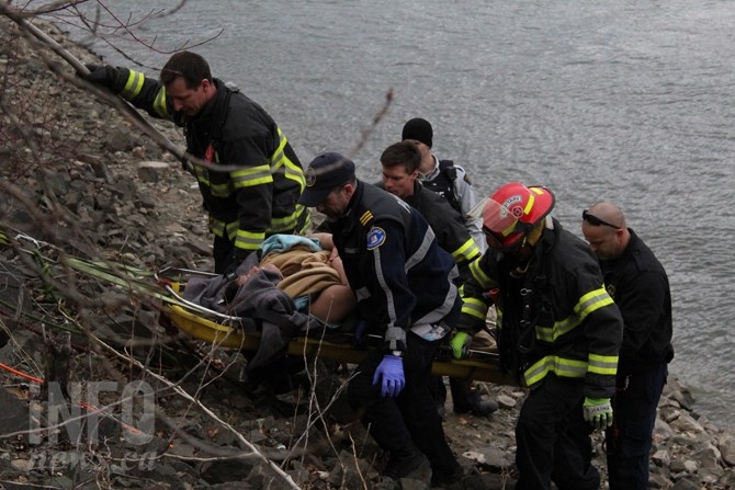 Members of Kamloops Fire Rescue, Kamloops RCMP and paramedics pull man up from river shore.