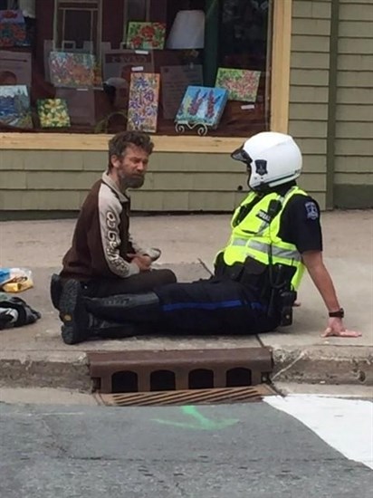 Community officer Const. Shawn Currie, right, sits down for a chat with a panhandler on the sidewalk in Halifax in this May 26, 2016, handout photo.