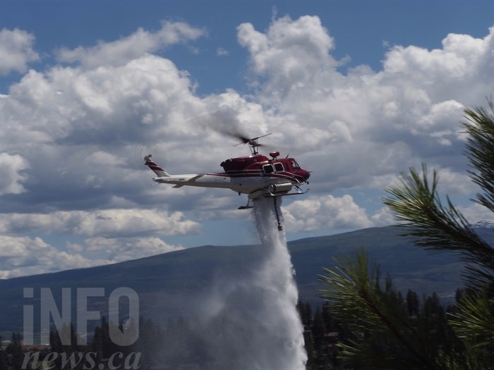 A helicopter drops a load of water on the wildfire burning on the hillside between Westside Road and Scott Crescent, Friday, June 17, 2016.