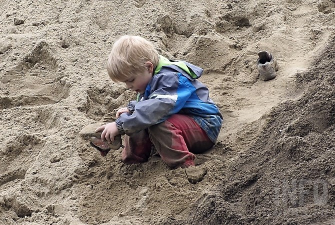 A Lake Country child empties sand from his shoes while his parents help shore up the banks of Duck Creek Thursday, May 11, 2017.