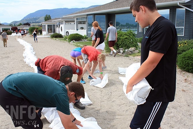 Lucas Golden, a grade 10 student at Pen-High, deposits a sandbag along the beach at Red Wing Resorts.