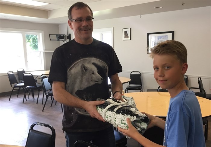 Froese's grandson Brody Passmore hands a completed mat to Regan, an outreach worker with New Life Community. 