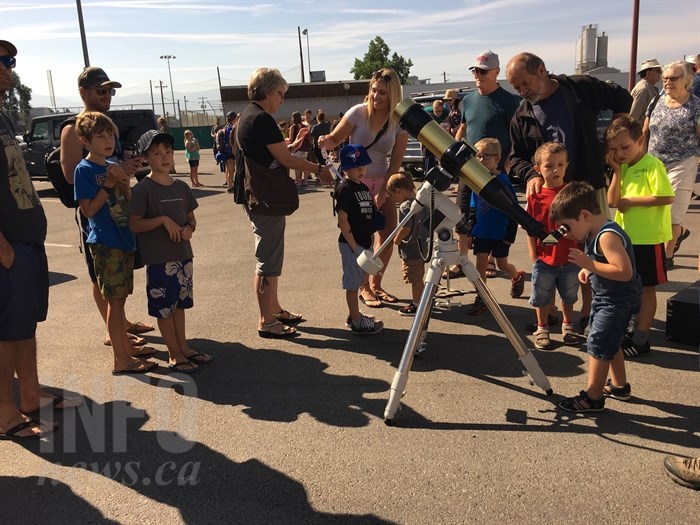Children look through a telescope, provided by the Okanagan Centre of the Royal Astronomical Society of Canada, to view the solar eclipse in Kelowna, Monday, Aug. 21, 2017.